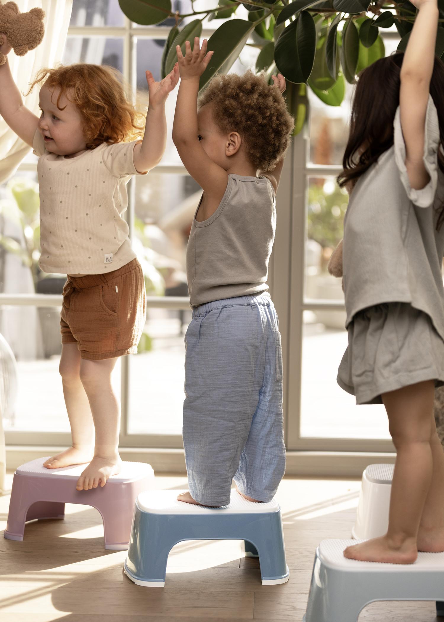Step stools in nice colours with kids playing - BabyBjörn